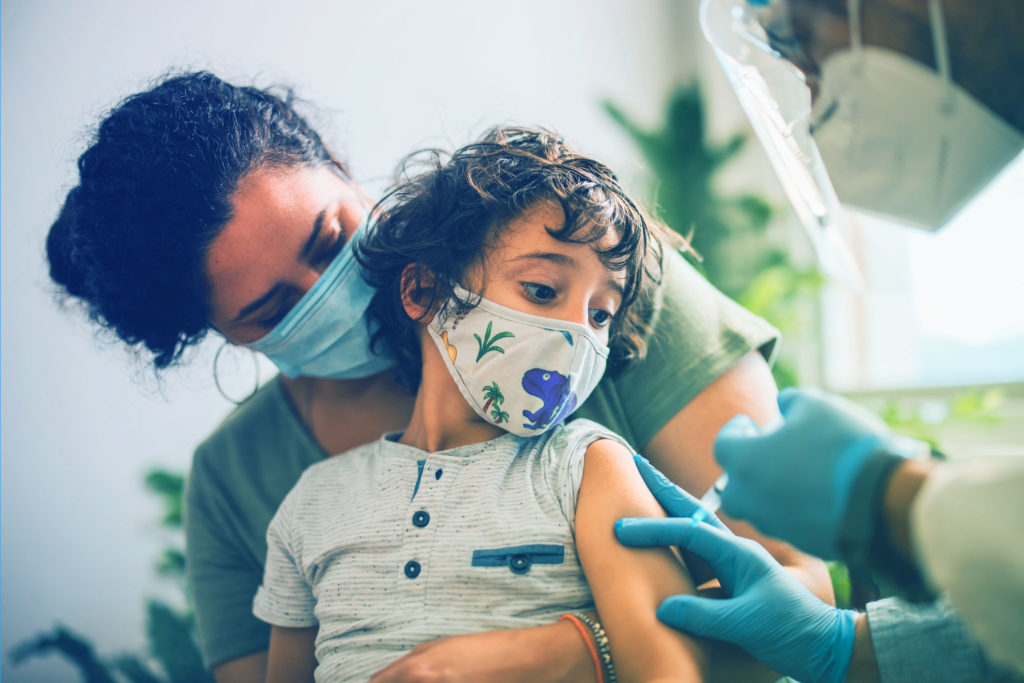 Kid receiving an immunization while sitting on mom's lap