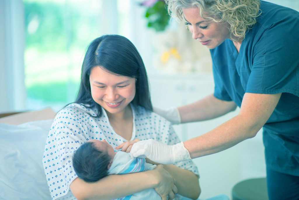 Mother receiving help from nurse with newborn