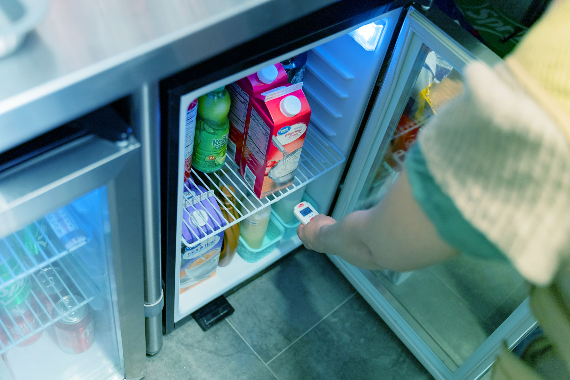 Person checking temperature in a refrigerator