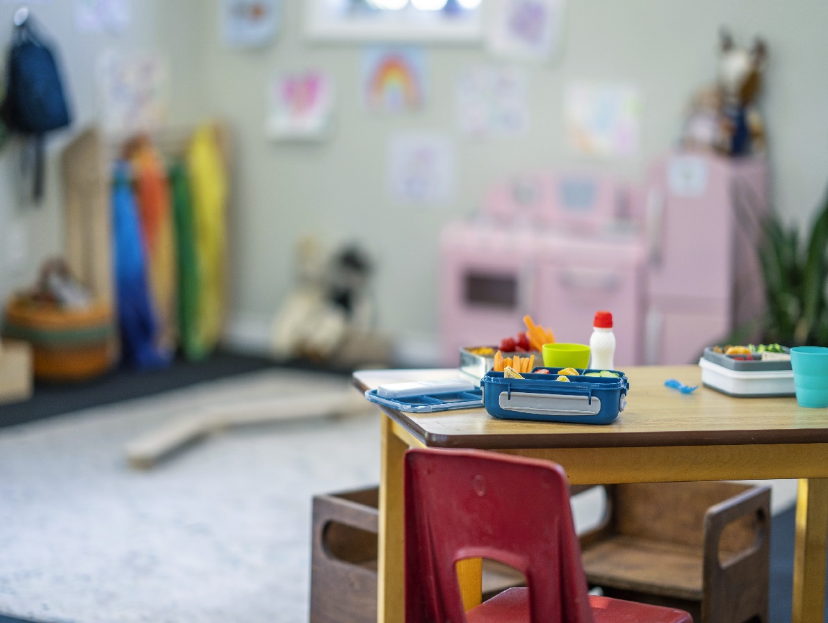 A table with children's lunch boxes sitting out is seen in an empty classroom