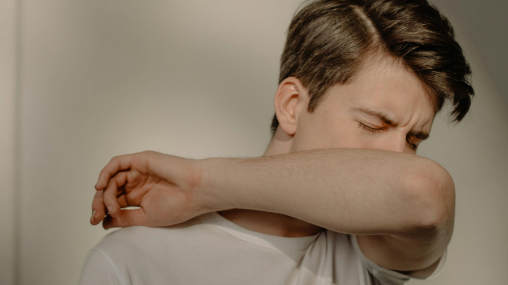 Boy coughing into his elbow